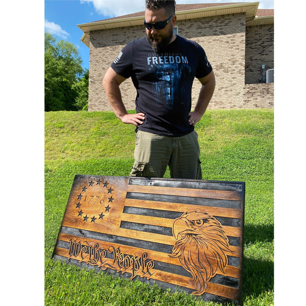 Patriot displaying We The People 1776 Wooden American Flag on grass, emphasizing its unique design and limited edition.